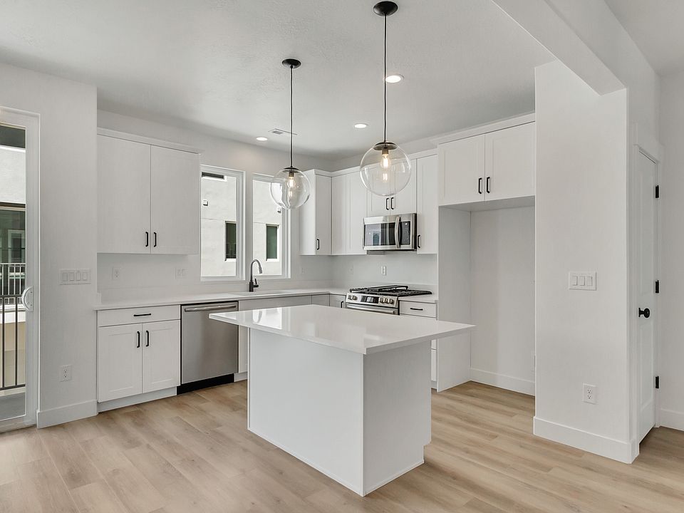 Modern kitchen with white cabinets, stainless steel appliances, island with pendant lights, light wo