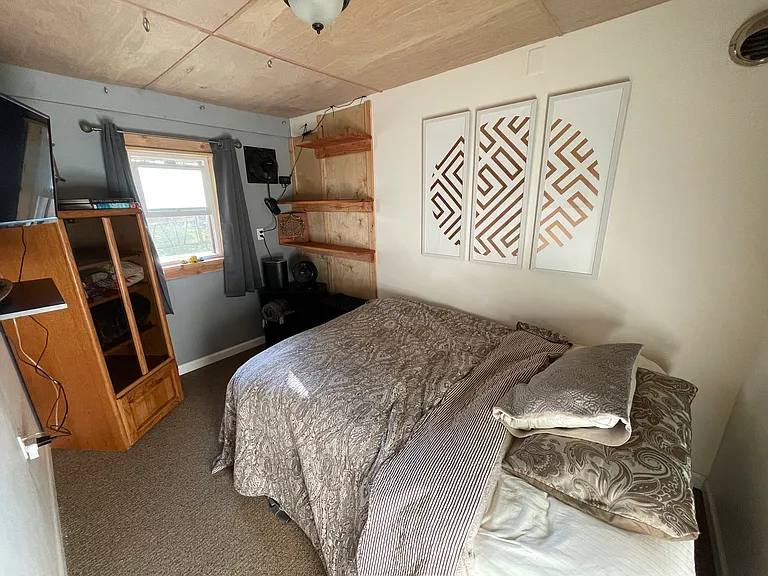 Second bedroom...very well insulated...partially furnished with mounted TV, Bed with pull out drawers, and cabinets.