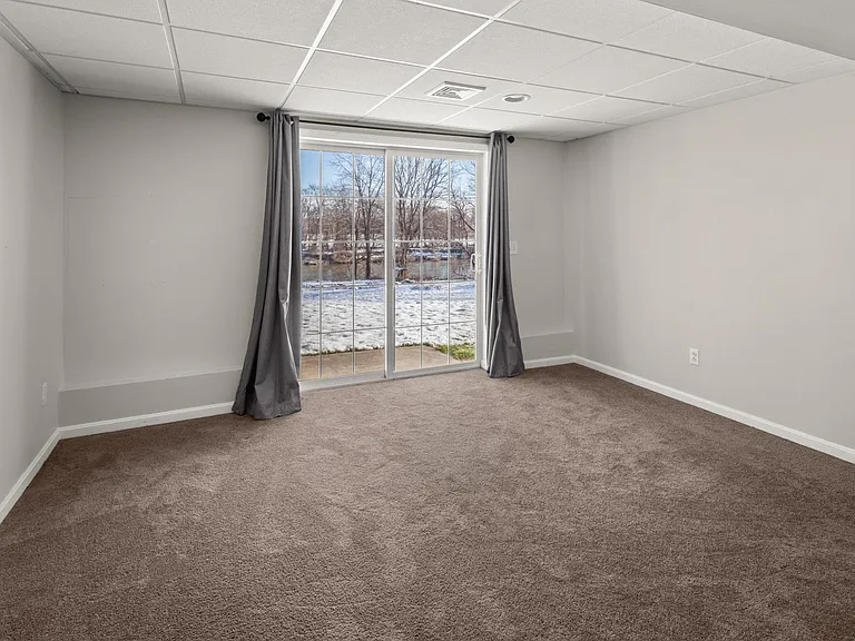 Bedroom with sliding glass door entryway to the backyard and overlooking the Winooski River.