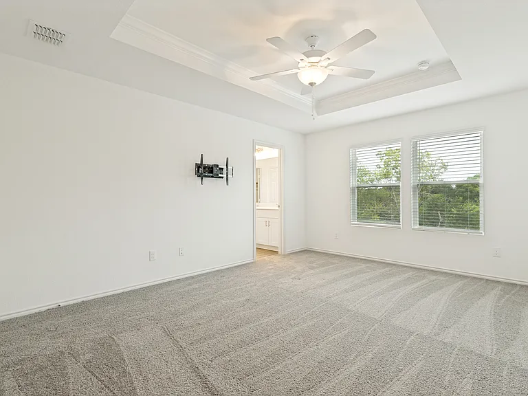 Large primary bedroom upstairs with beautiful trayed ceiling and ceiling fan.