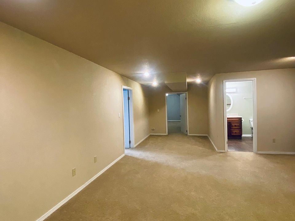View from living area into both bedrooms on the left and bathroom on the right. Large space, new carpet