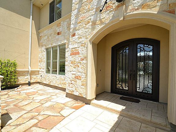 Front doorway with stone accents and a flagstone courtyard.