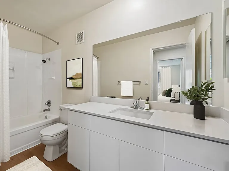 Renovated Package II bath with white quartz countertop, updated white cabinetry, and hard surface flooring