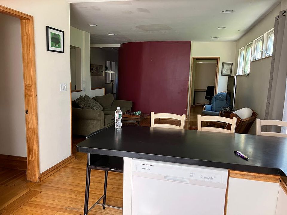 The kitchen is adjacent to one bedroom and faces another bedroom across the living room.