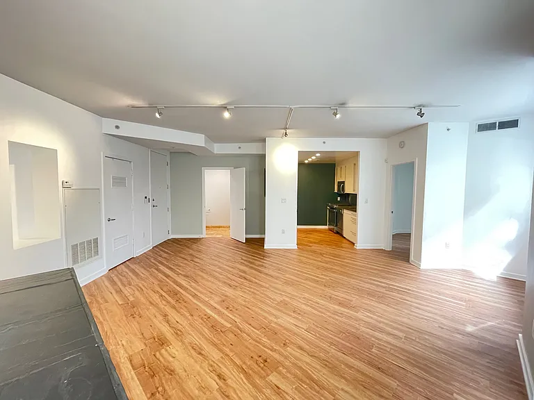 living space, without furniture. From bottom left corner: You see the stone fireplace, master bedroom door (not visible in picture), utility/storage room door, front entry door, 2nd bathroom door (wide open in picture), the kitchen, 2nd BR door