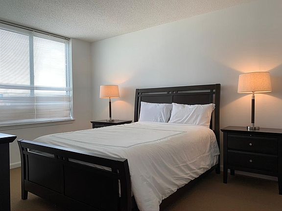 Master bedroom with two night stands, dresser, and ample closets with custom built-in shelving.