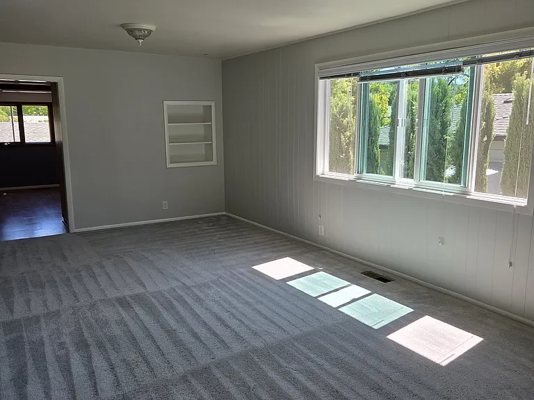 Living room looking towards side of house and kitchen in distance