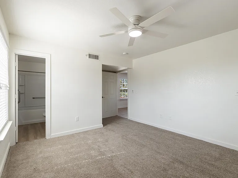 Bright and spacious bedroom with plush carpet, ceiling fan, and natural light from window, featuring an ensuite bathroom. Bright and spacious bedroom with plush carpet, ceiling fan, and natural light from window, featuring an ensuite bathroom.