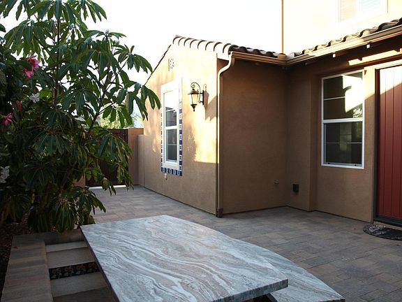 Spacious courtyard with large granite table and chair. Luscious, mature landscaping and beautiful decorated tile accents.