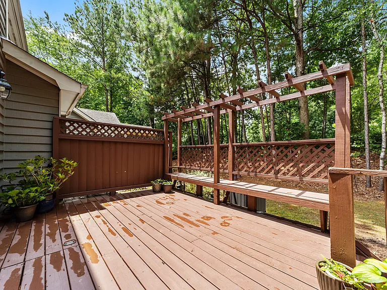 Private rear deck with pergola seating and a peaceful wooded backdrop.