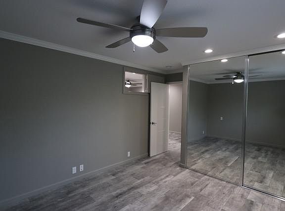 Bedroom with floor to ceiling mirrored closet doors and ceiling fan