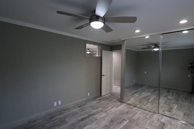 Bedroom with floor to ceiling mirrored closet doors and ceiling fan