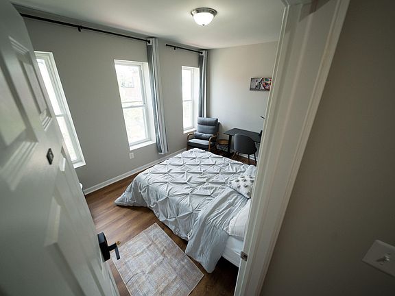 Private bedroom with multiple windows, hardwood floors, and space for a bed plus a dedicated desk/work area.
