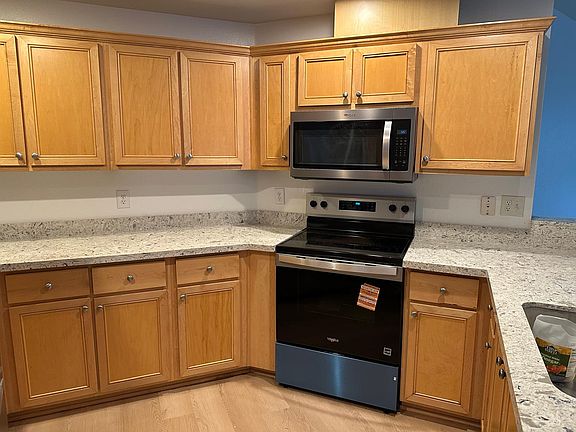 Kitchen area with new quartz countertops, stove, flooring, and microwave hood