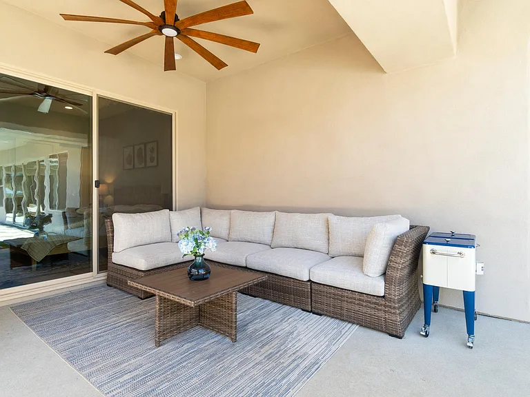 The outdoor covered patio features a cozy sectional with overhead lighting and a breeze coming from the ceiling fan.