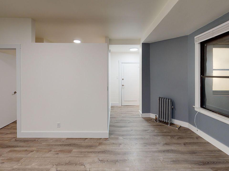 Sunlit room with a large window and wood-like flooring