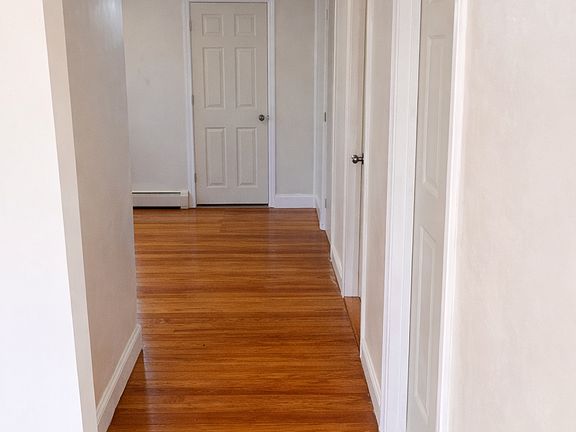 Hallway from living area leading to dining/ kitchen, & doors to bathroom, storage closet, and 3 bedrooms.