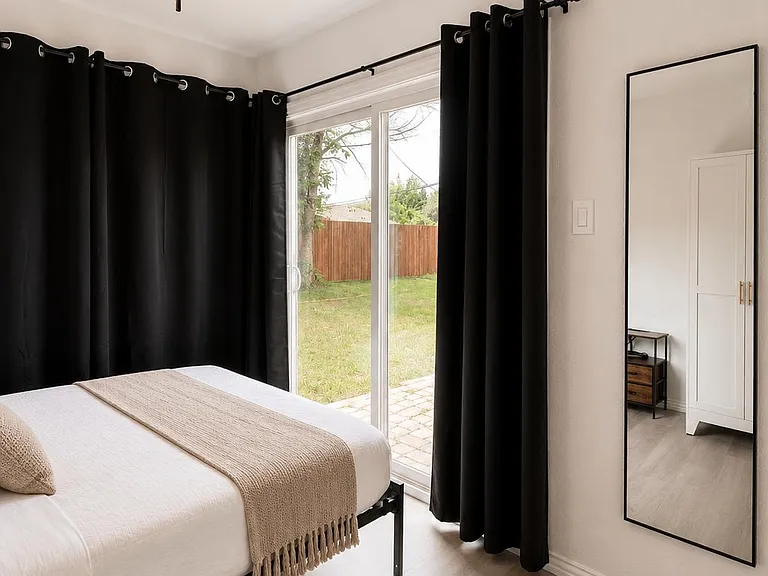 Bedroom features a ceiling fan, large sliding glass doors to the backyard, and ample space for storage and furnishings.