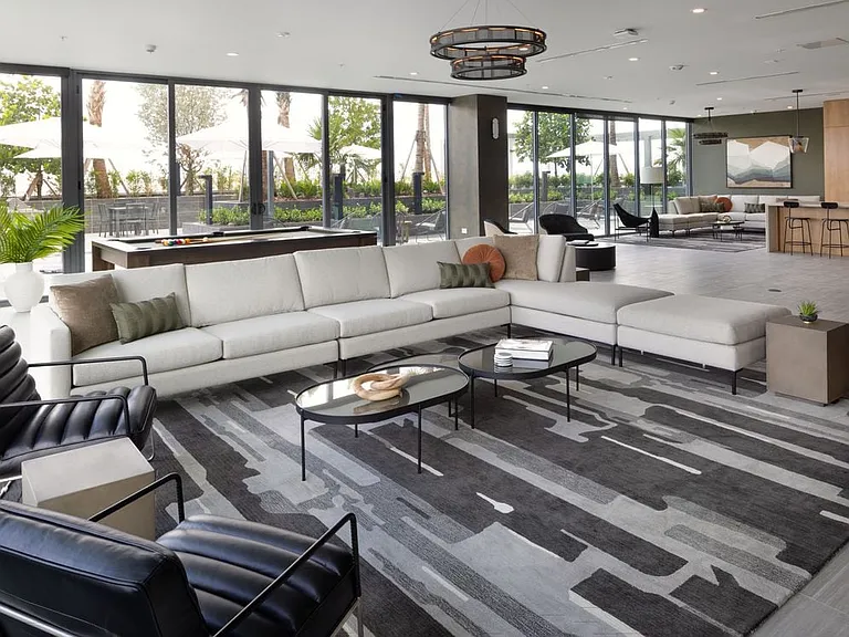 Resident lounge with modern seating, pool table, kitchenette, and pool deck views