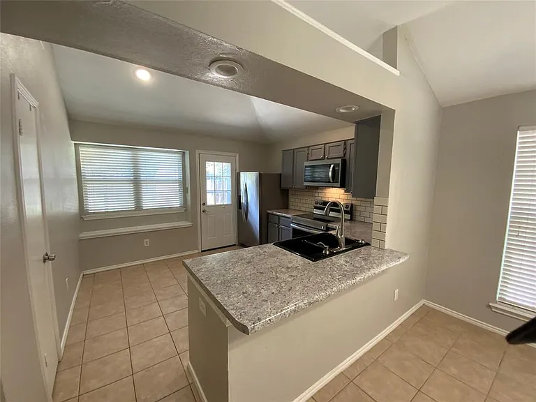 Kitchen featuring a breakfast bar with stone-finish countertop, stainless steel appliances, subway tile backsplash, and dark cabinetry