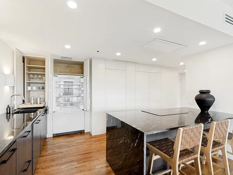 The solid core doors and panels add a quality feel to the cabinetry. In this photo, the bar cleverly uses left over space while the double-door Fisher & Paykel refrigerator with a lower freezer is hidden behind matching wood panels.