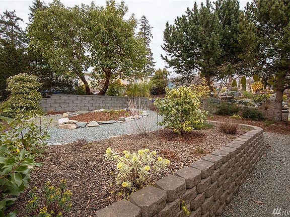 Street side landscaped for easy maintenance. RV parking is now available to the front of the home. This graveled area could be enhanced for a larger RV? Gravel path leads to the side of the home where the storage building is located.