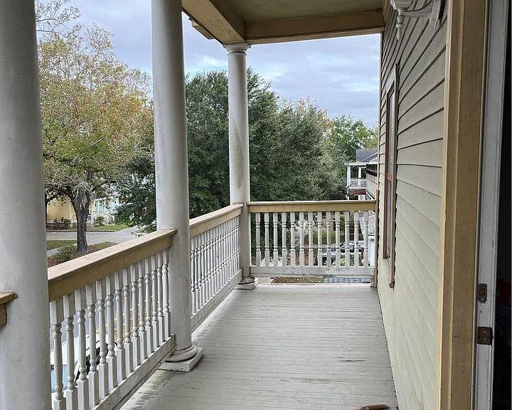 Classic Savannah covered front porch with columns and a treetop view of the neighborhood.