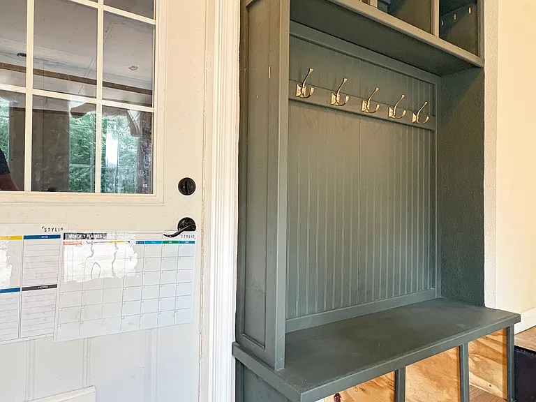 Thoughtfully positioned beside three entryways, the custom-built mudroom bench creates an ideal organization hub, making it easy to keep everyday items neatly stored and within reach.