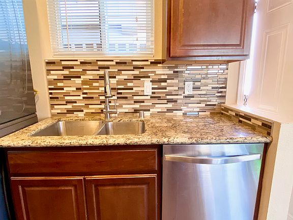 Granite counter with deep stainless steel sink and stainless dishwasher.