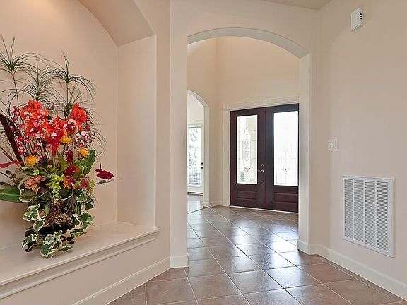 Breathtaking foyer boasts triple crown moulding, arched openings, art niche, diagonally laid tile flooring, 2-story ceiling with a beautiful wrought iron chandelier and an 8' wide grand corridor leading to the dining and living areas.