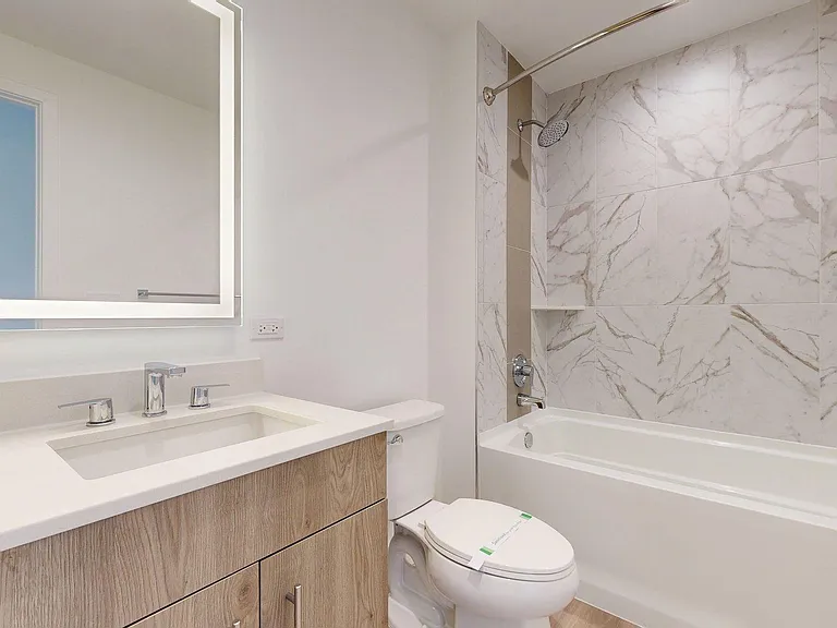 Apartment Bathroom with large soaking tub, LED vanity mirror and hardwood floors.