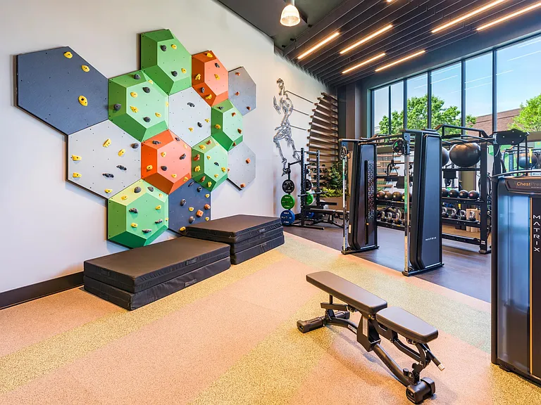Elevate your workout in our one-of-a-kind fitness center_featuring a rock climbing wall, strength training gear, and energizing natural light.