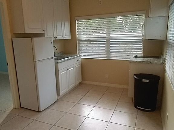 West view of Kitchen. Lots cabinet space, simple sink and apartment refrigerator.