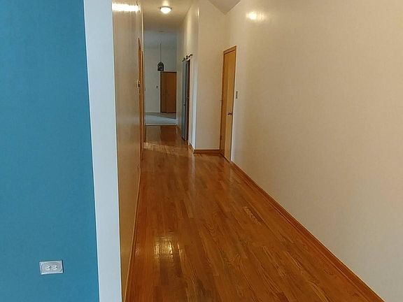 Long hallway through the side of the unit. Hardwood floors.