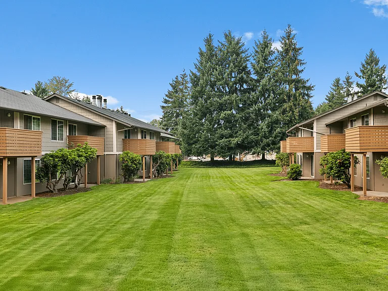Spacious green courtyard surrounded by apartment homes with private balconies.