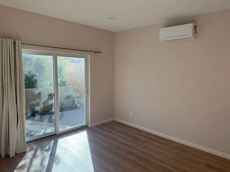 Downstairs bedroom with split A/C unit and sliding patio doors