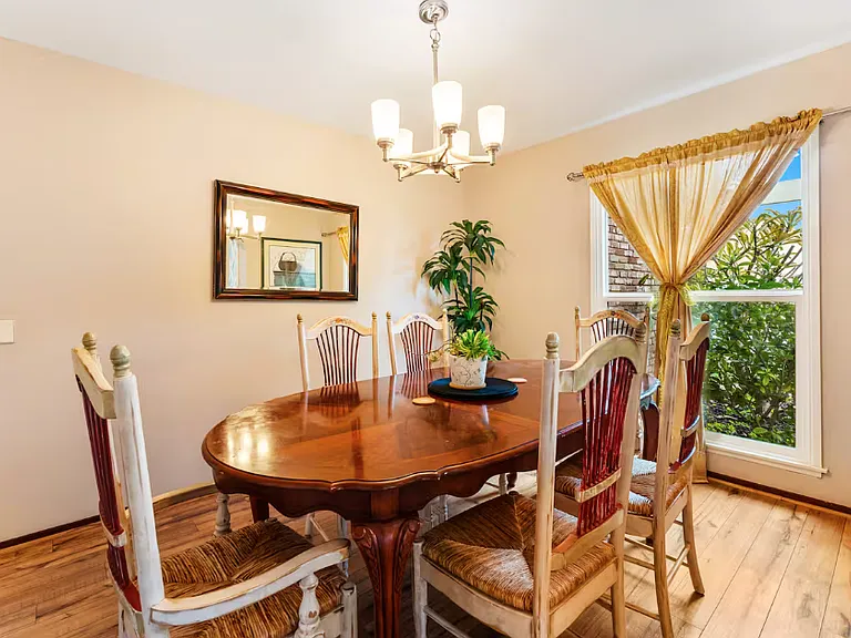 Spacious formal dining room with wooden flooring and big window with view of the front garden.