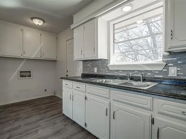 Utility area with washer/dryer hookups. Door to garage is on the left and door to backyard on the right