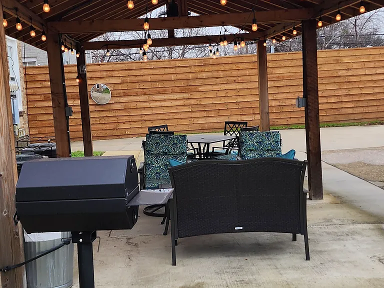Back patio, with fans, string lights, seating and grill.