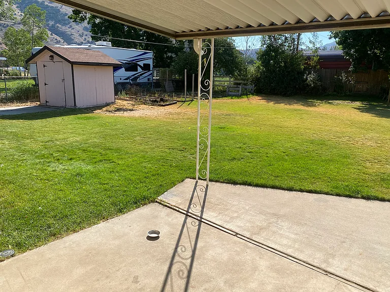 Huge backyard with fire pit, clothesline, garden boxes, shed, covered patio, mature trees, and plenty of room to play/relax.