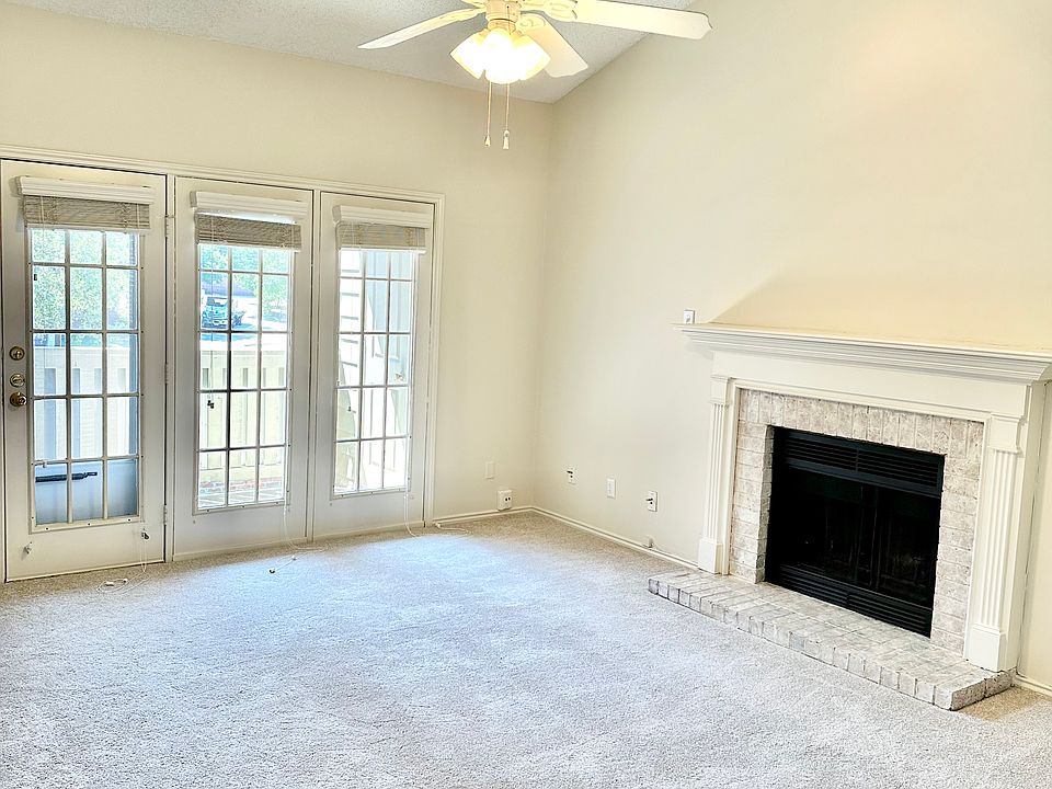 Living room with vaulted ceilings; carpet is less than 2 years old . Wood burning fireplace . Balcony overlooking grassy area with trees.