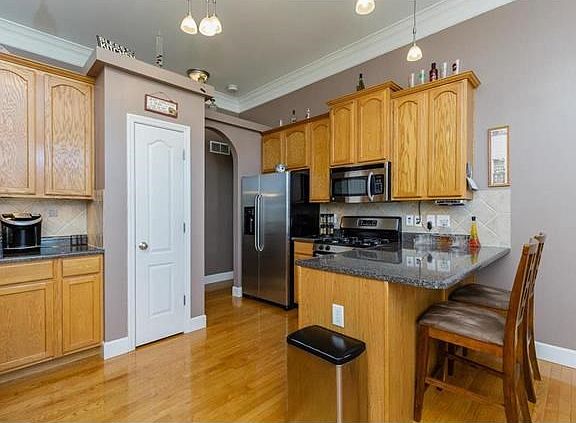 Awesome kitchen with stainless appliances, breakfast bar, tile backsplash, pantry and hardwood floor