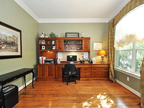 Large study with custom drapes, crown molding, French doors.