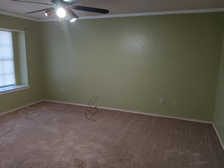 Spacious master bedroom with window seat, ceiling fan, crown moulding, plush carpet.