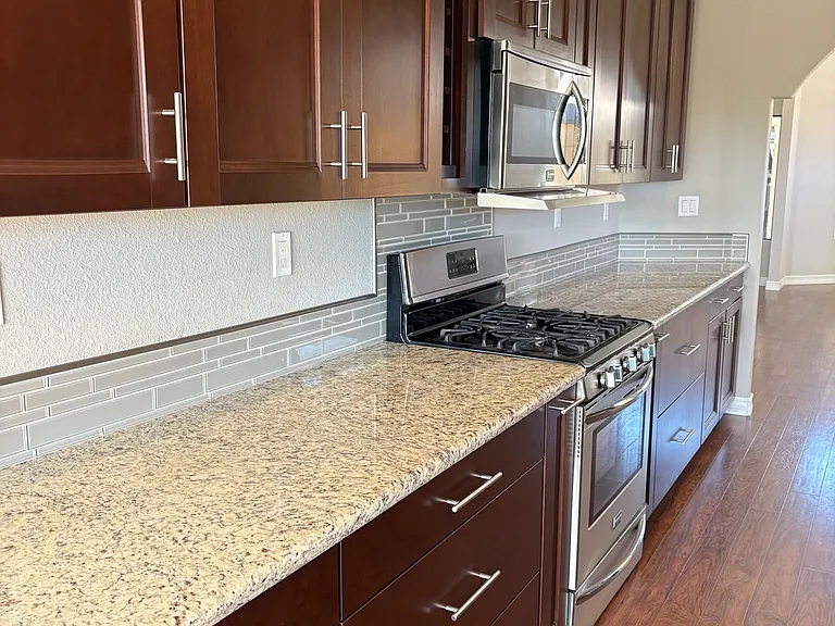 Kitchen with stainless appliances with gas stove and vent hood microwave.
