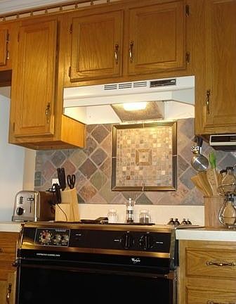 Kitchen has tile backsplash around the counters