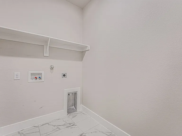 Laundry area featuring a built-in shelf, white walls, and marble-look floor tiles