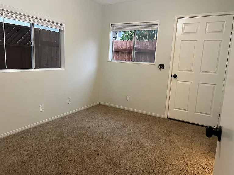 Bedroom very light with two windows and door to small private patio.