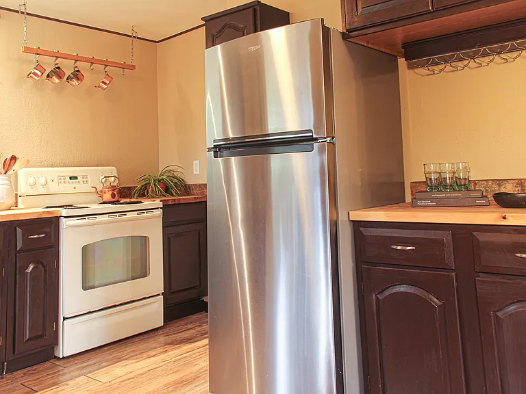 The kitchen with new Whirlpool fridge, pot rack, hanging wine rack, and more counter space.