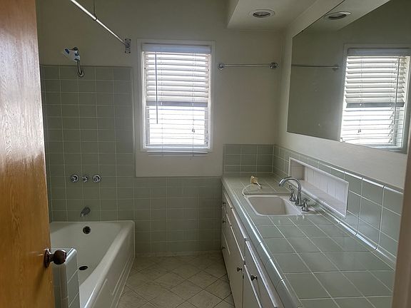 Master bathroom with great lighting, an overhead heating lamp, a long counter, a tub, and a shower.